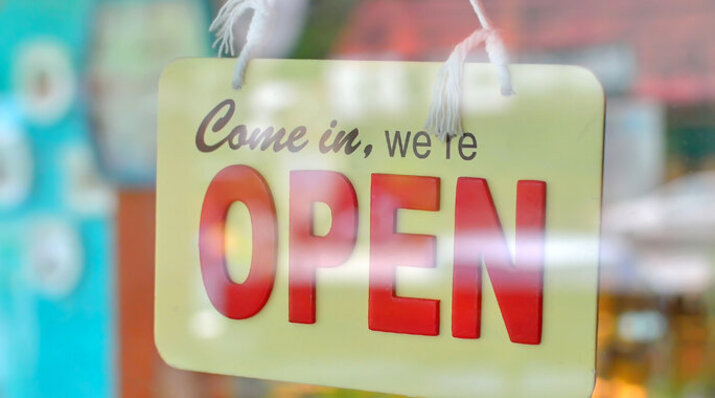 "We are open", Schild hinter einer Glastür